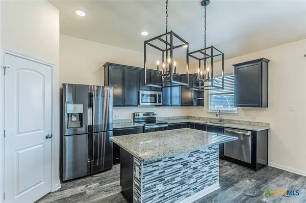 a kitchen with stainless steel appliances granite countertop a sink refrigerator and microwave