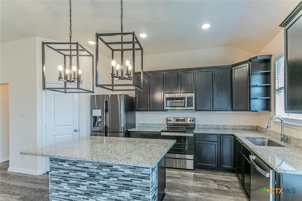 a kitchen with stainless steel appliances granite countertop a sink stove and refrigerator