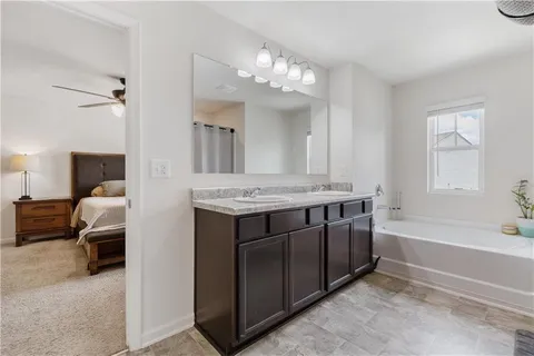 a spacious bathroom with a tub double sink and mirror