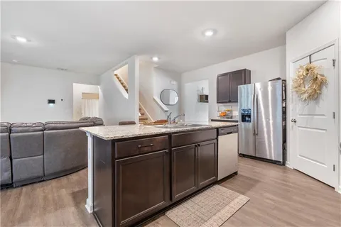 a kitchen with stainless steel appliances granite countertop a sink a stove a refrigerator and island with wooden floor