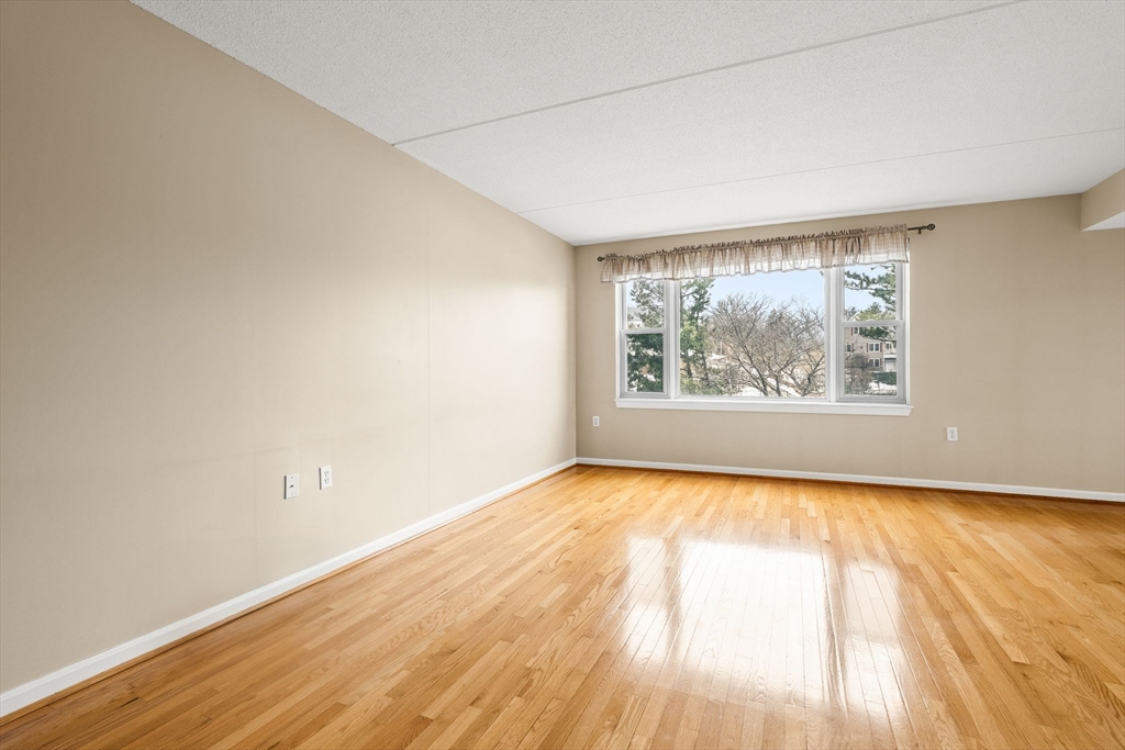 155 George Washington Boulevard, Unit 210 Hull, MA 02045 - Photo 14 of 42 an empty room with wooden floor and windows