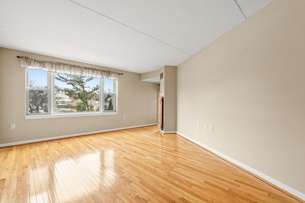 155 George Washington Boulevard, Unit 210 Hull, MA 02045 - Photo 15 of 42 a view of an empty room with wooden floor and a window