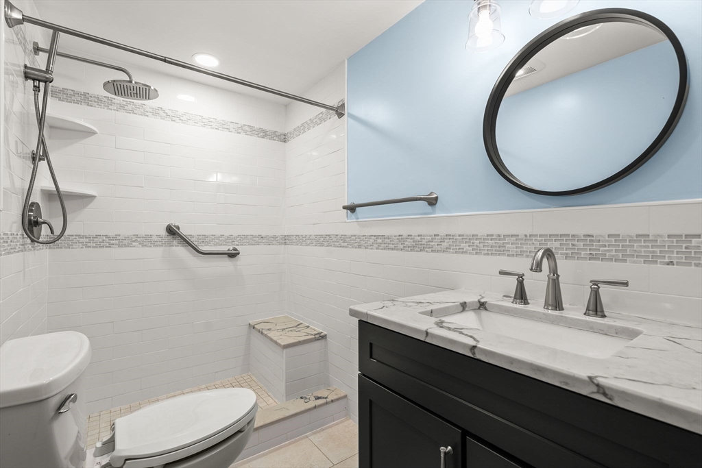 155 George Washington Boulevard, Unit 210 Hull, MA 02045 - Photo 19 of 42 a bathroom with a granite countertop sink mirror vanity and toilet
