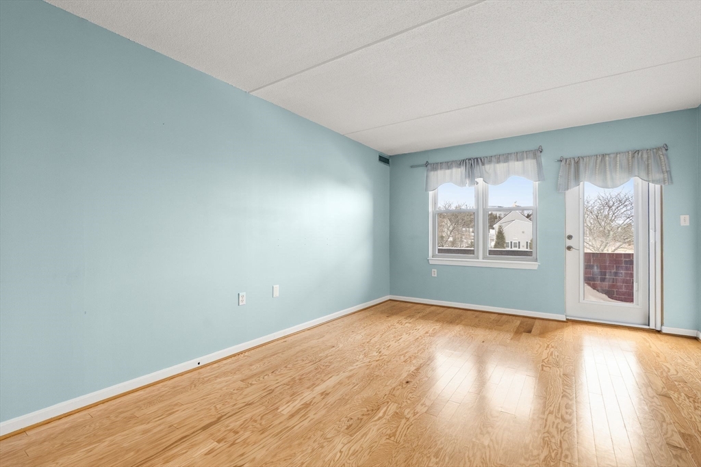 155 George Washington Boulevard, Unit 210 Hull, MA 02045 - Photo 26 of 42 an empty room with wooden floor and windows