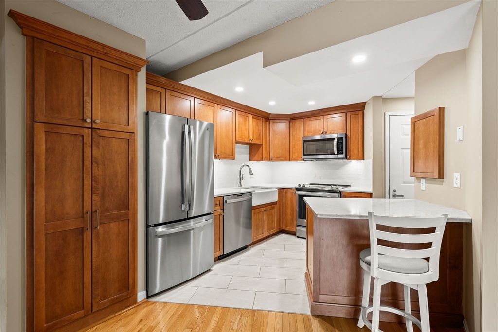 155 George Washington Boulevard, Unit 210 Hull, MA 02045 - Photo 5 of 42 a kitchen with stainless steel appliances granite countertop a refrigerator a sink dishwasher a stove and a refrigerator with wooden floor