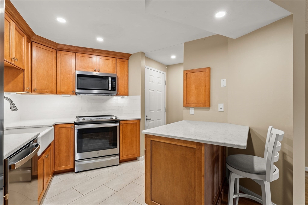 155 George Washington Boulevard, Unit 210 Hull, MA 02045 - Photo 6 of 42 a kitchen with a stove a sink and a microwave