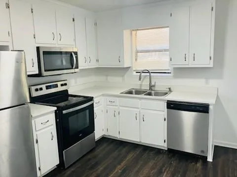 a kitchen with granite countertop white cabinets sink and stainless steel appliances