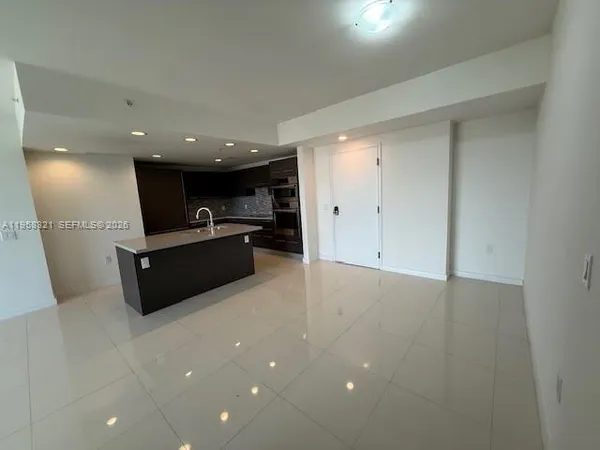 a large room with stainless steel appliances kitchen island sink refrigerator and microwave
