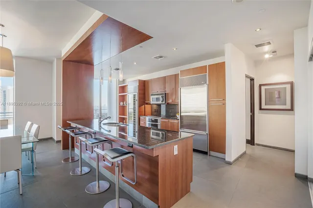 a kitchen with stainless steel appliances granite countertop a table chairs and a refrigerator