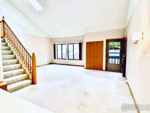 a view of an empty room with window and stairs