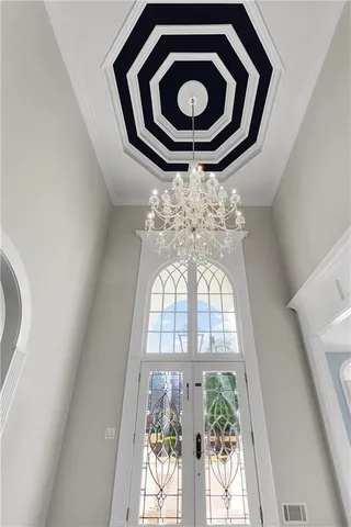 an empty room with wooden floor chandelier fan and windows