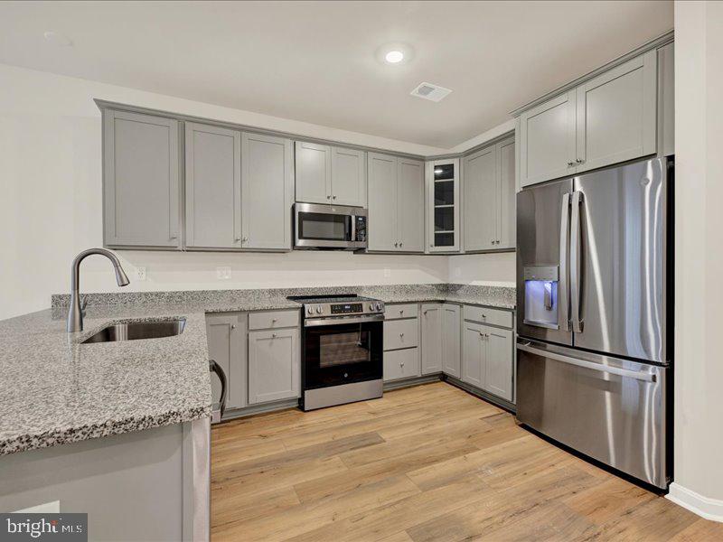 a kitchen with granite countertop a refrigerator stove and sink