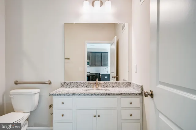 a bathroom with a granite countertop toilet sink and mirror