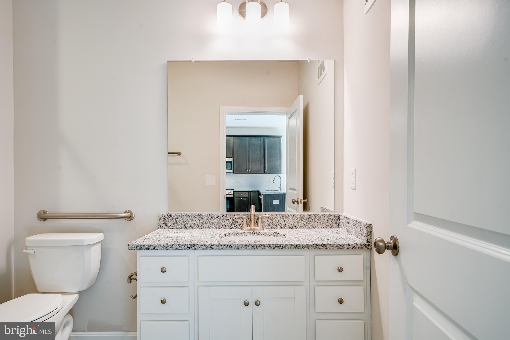4003 Seaside Alder Road, Unit 102 ASTER Bowie, MD 20720 - Photo 13 of 16 a bathroom with a granite countertop toilet sink and mirror