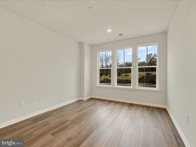 4003 Seaside Alder Road, Unit 102 ASTER Bowie, MD 20720 - Photo 18 of 27 an empty room with wooden floor and windows