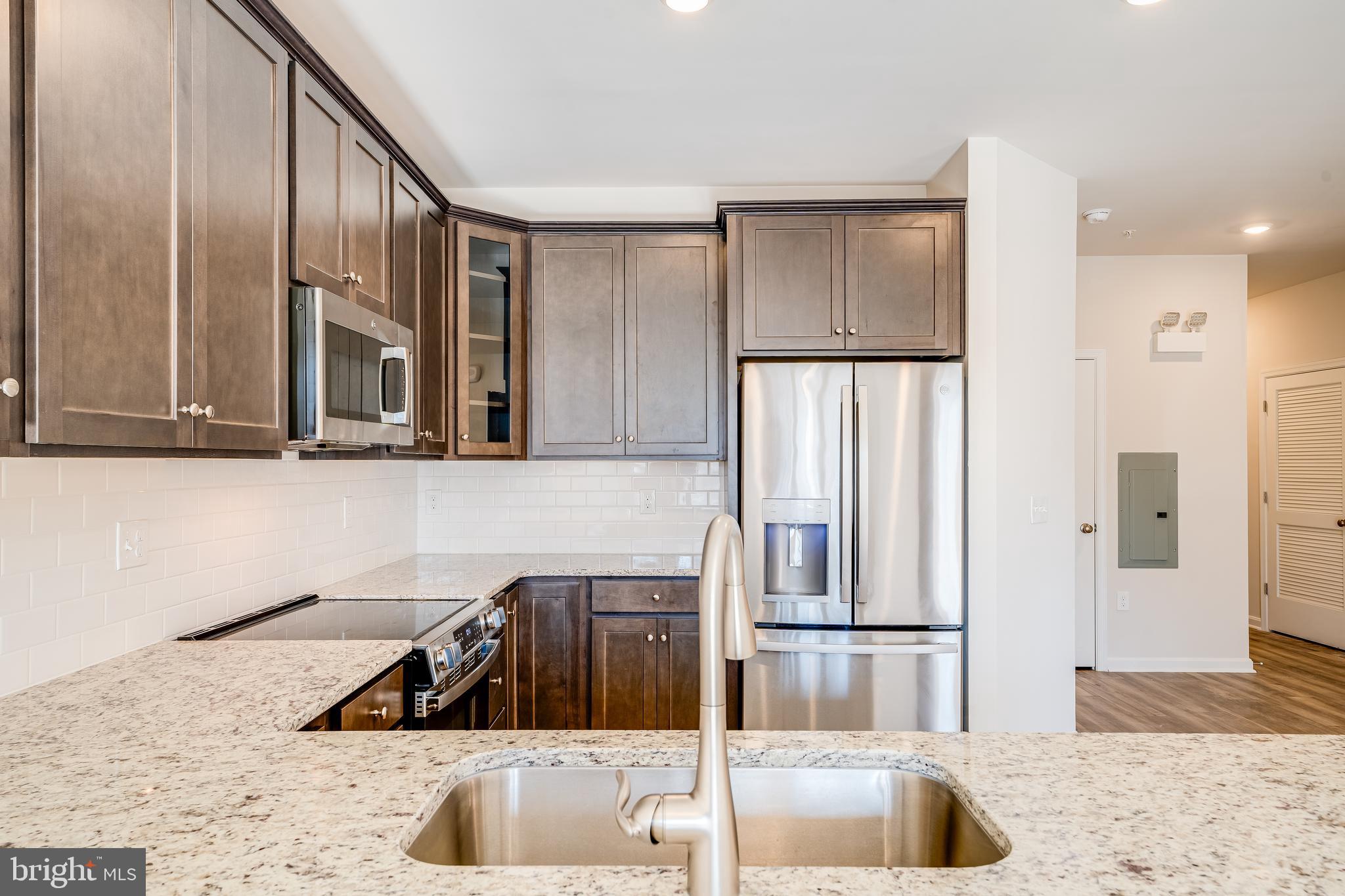 4003 Seaside Alder Road, Unit 102 ASTER Bowie, MD 20720 - Photo 4 of 16 a kitchen with stainless steel appliances granite countertop a refrigerator and a sink