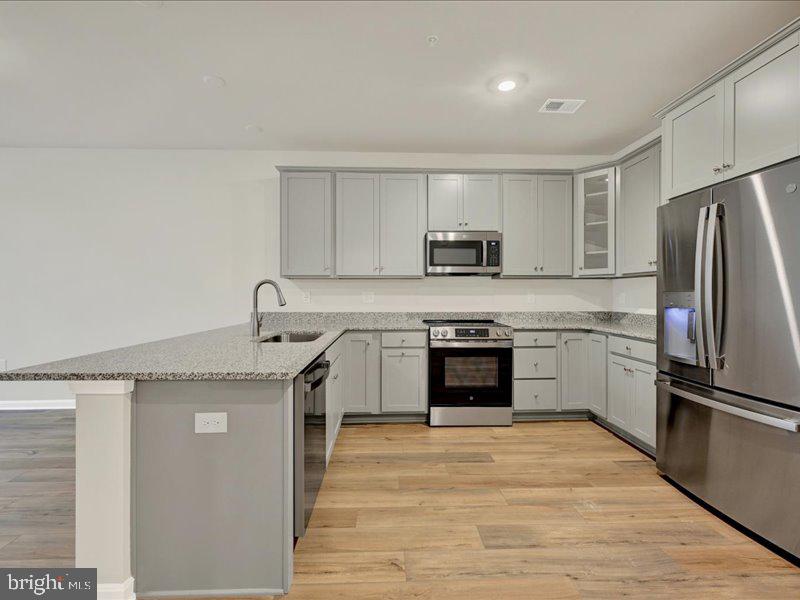 4003 Seaside Alder Road, Unit 102 ASTER Bowie, MD 20720 - Photo 5 of 27 a kitchen with a stove top oven and refrigerator