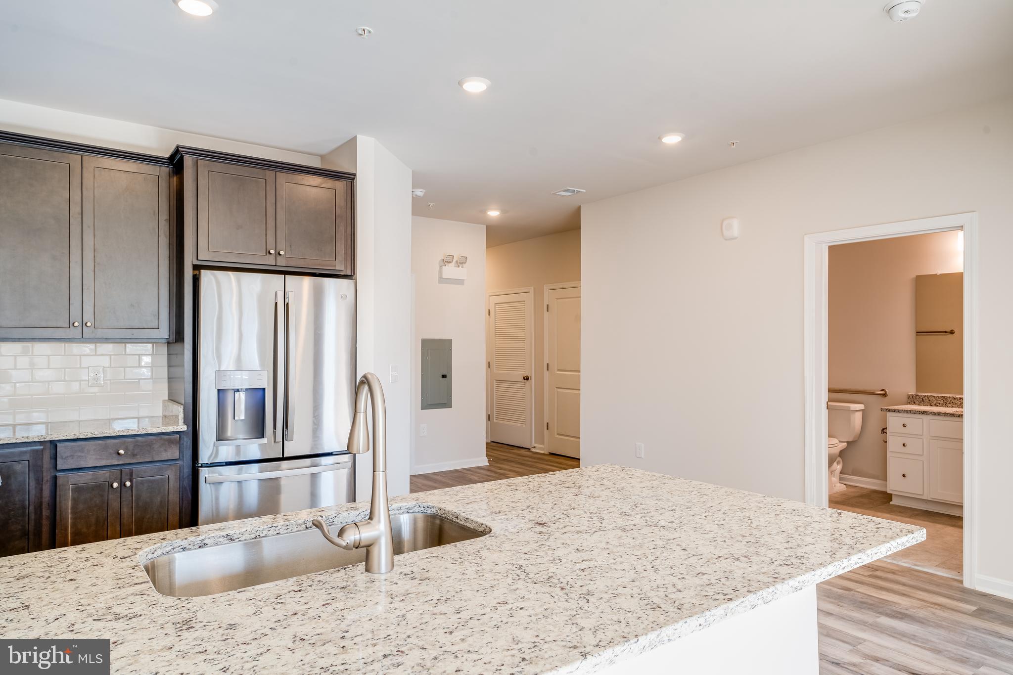 4003 Seaside Alder Road, Unit 102 ASTER Bowie, MD 20720 - Photo 5 of 16 a kitchen with stainless steel appliances kitchen island granite countertop a refrigerator and a sink