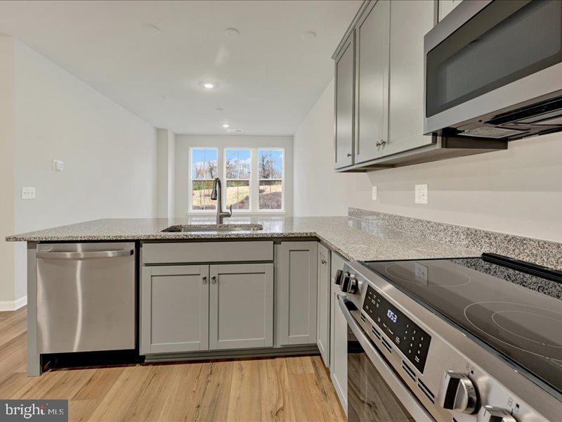 4003 Seaside Alder Road, Unit 102 ASTER Bowie, MD 20720 - Photo 8 of 27 a kitchen with granite countertop a sink a stove and cabinets