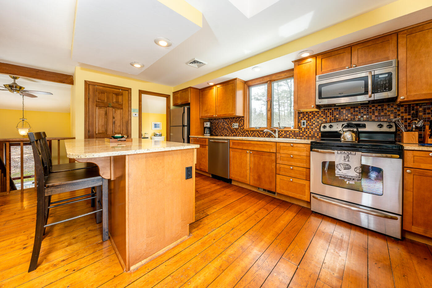 150 Herring Brook Road Eastham, MA 02642 - Photo 13 of 54 a kitchen with stainless steel appliances granite countertop a stove top oven a sink dishwasher a dining table and chairs with wooden floor
