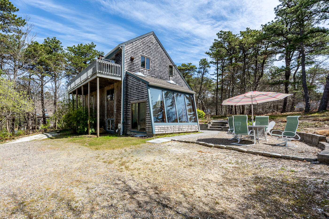 150 Herring Brook Road Eastham, MA 02642 - Photo 3 of 54 a patio with a table and chairs under an umbrella
