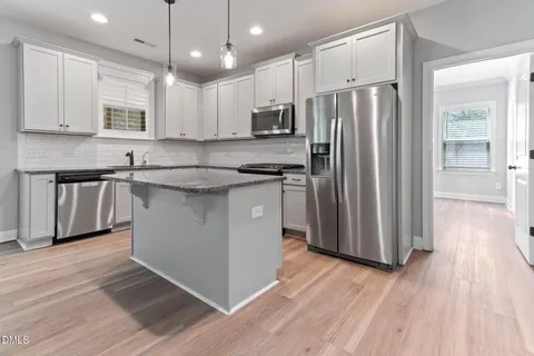 a kitchen with stainless steel appliances granite countertop a sink a stove and a refrigerator