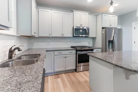 an empty room with windows fireplace and a sink