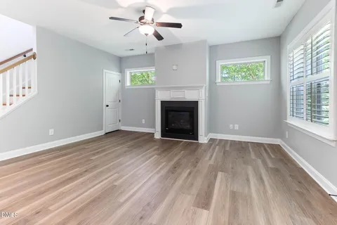 an empty room with windows fireplace and wooden floor