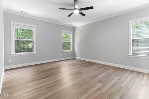 an empty room with wooden floor and ceiling fan
