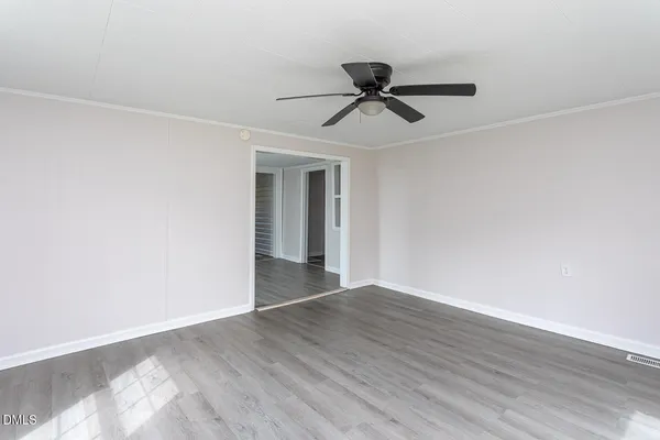 a view of an empty room with wooden floor and closet