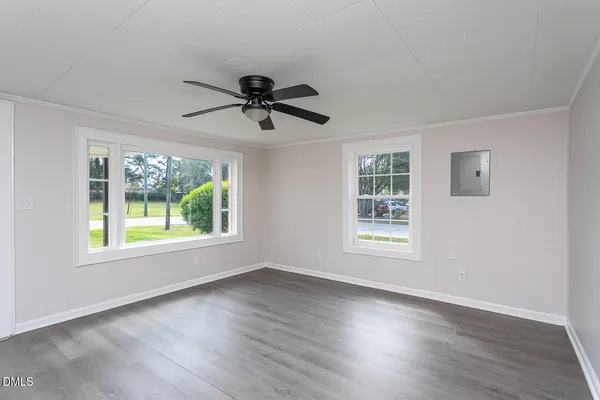 a view of an empty room with wooden floor and windows
