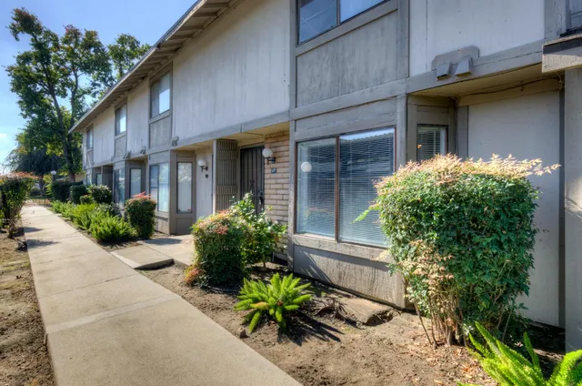 a view of a house with potted plants and a table and chairs