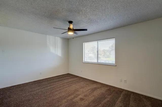 an empty room with a window and a ceiling fan