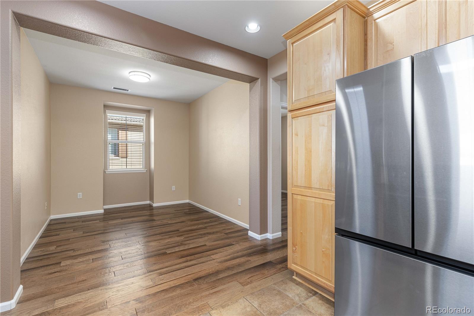 3301 Cascina Circle, Unit C Highlands Ranch, CO 80126 - Photo 15 of 40 a view of a refrigerator in kitchen and an empty room with wooden floor