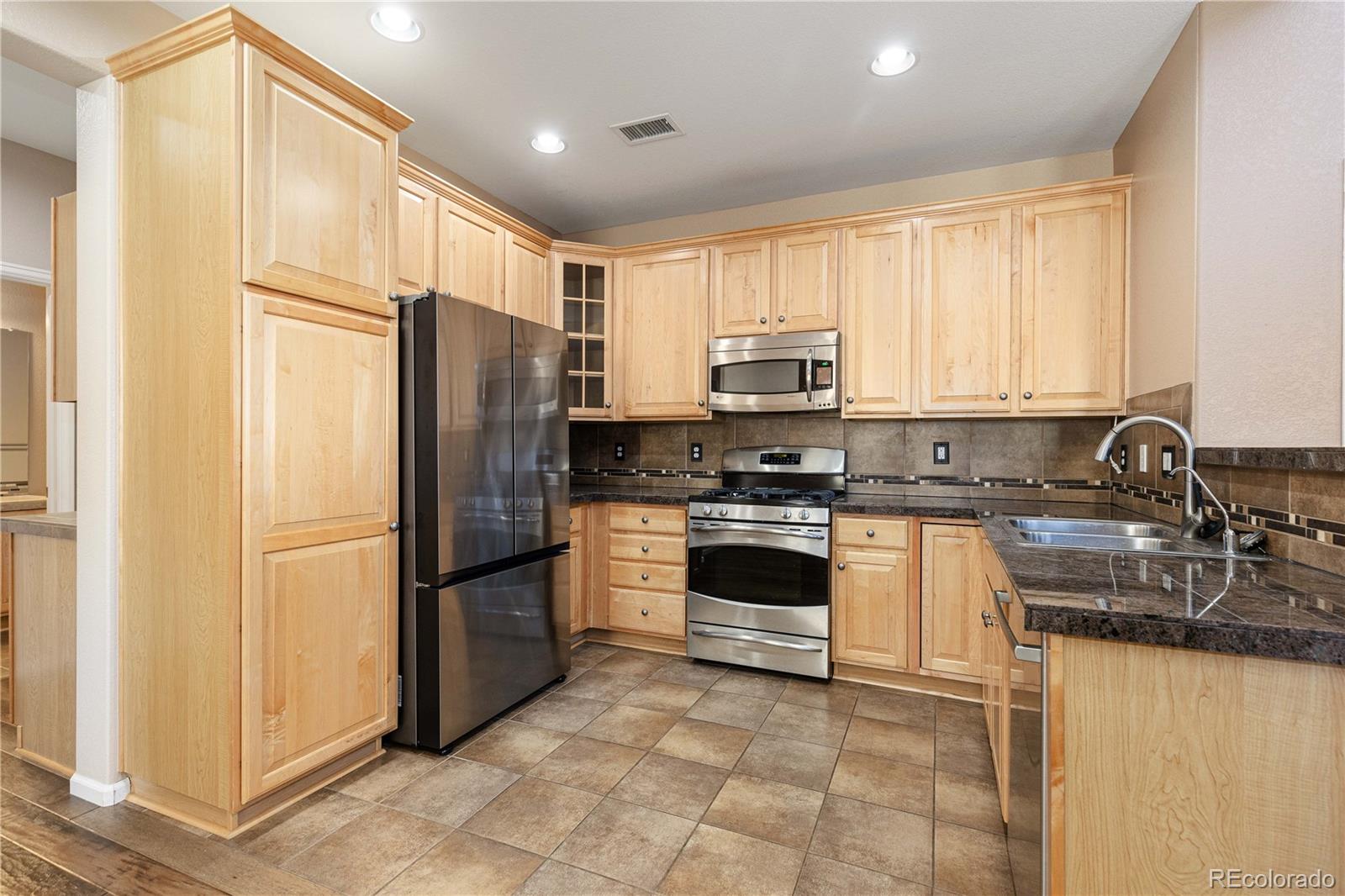 3301 Cascina Circle, Unit C Highlands Ranch, CO 80126 - Photo 20 of 40 a kitchen with granite countertop a refrigerator stove and sink
