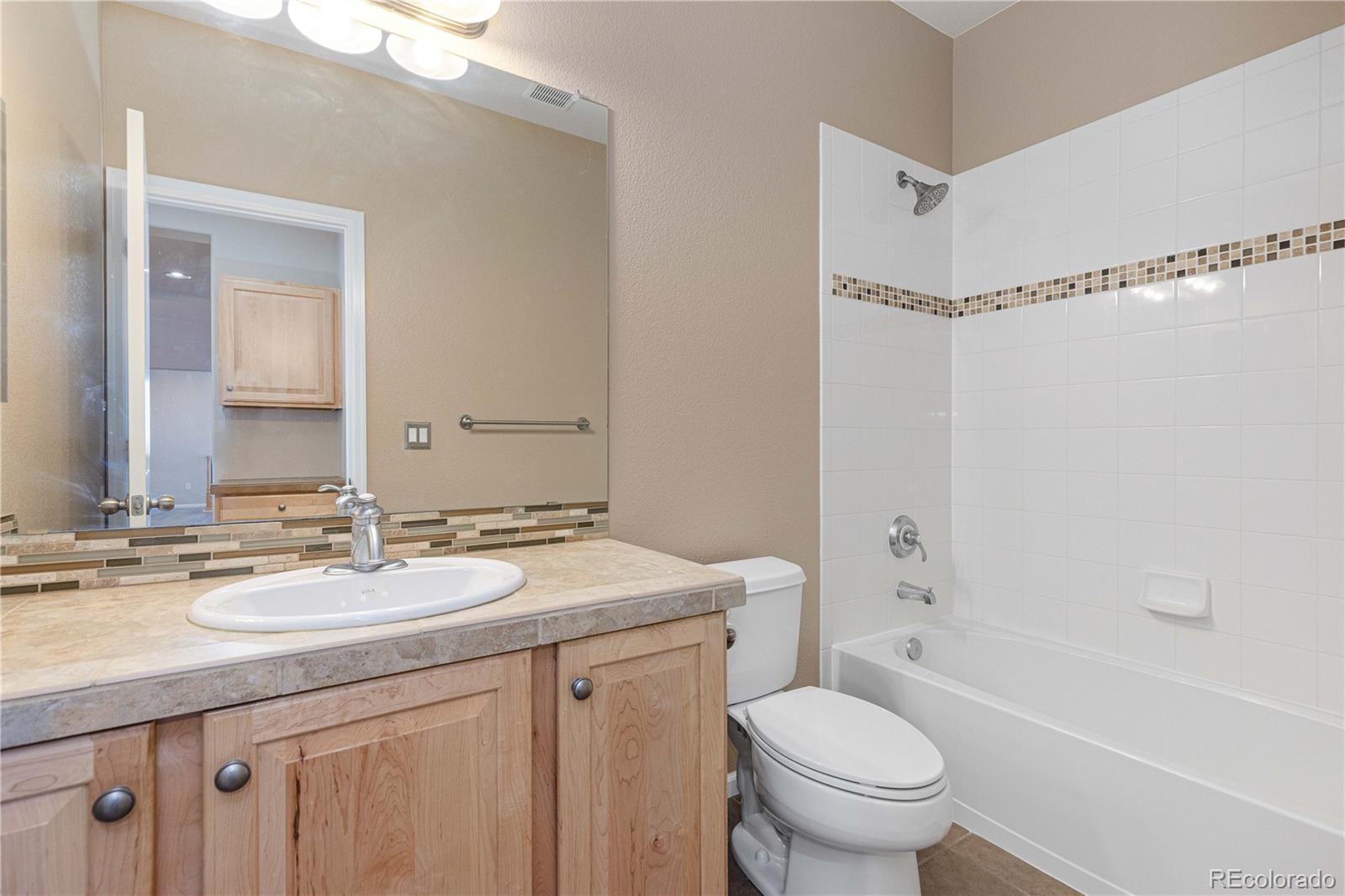 3301 Cascina Circle, Unit C Highlands Ranch, CO 80126 - Photo 22 of 40 a bathroom with a granite countertop sink a toilet a mirror a bathtub and shower