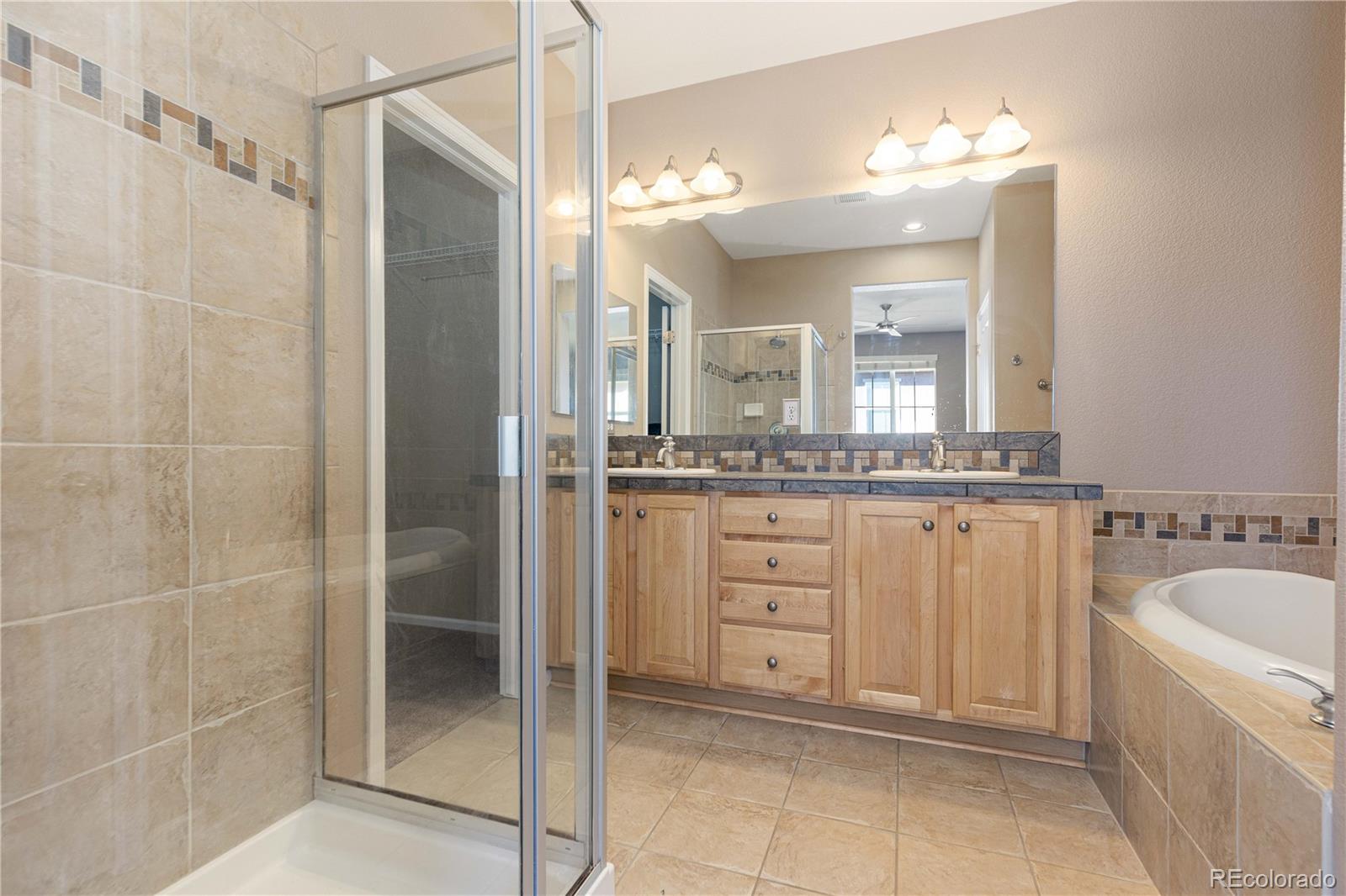 3301 Cascina Circle, Unit C Highlands Ranch, CO 80126 - Photo 29 of 40 a bathroom with a granite countertop sink a mirror and a bathtub