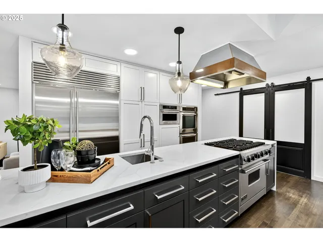 a kitchen with stainless steel appliances kitchen island granite countertop a sink a stove and a wooden floors