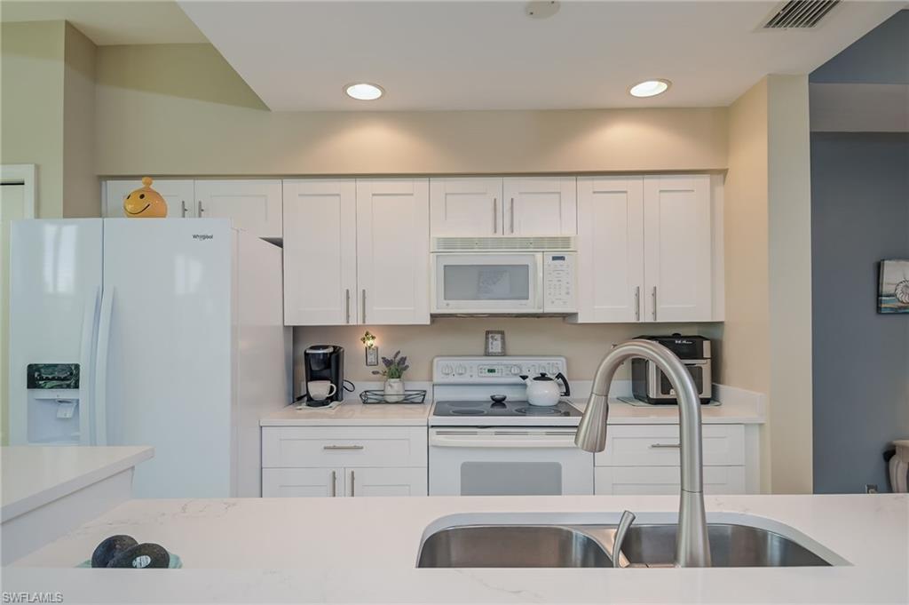 8670 Cedar Hammock Circle, Unit 223 Naples, FL 34112 - Photo 8 of 27 a kitchen with kitchen island a white counter top space cabinets and stainless steel appliances