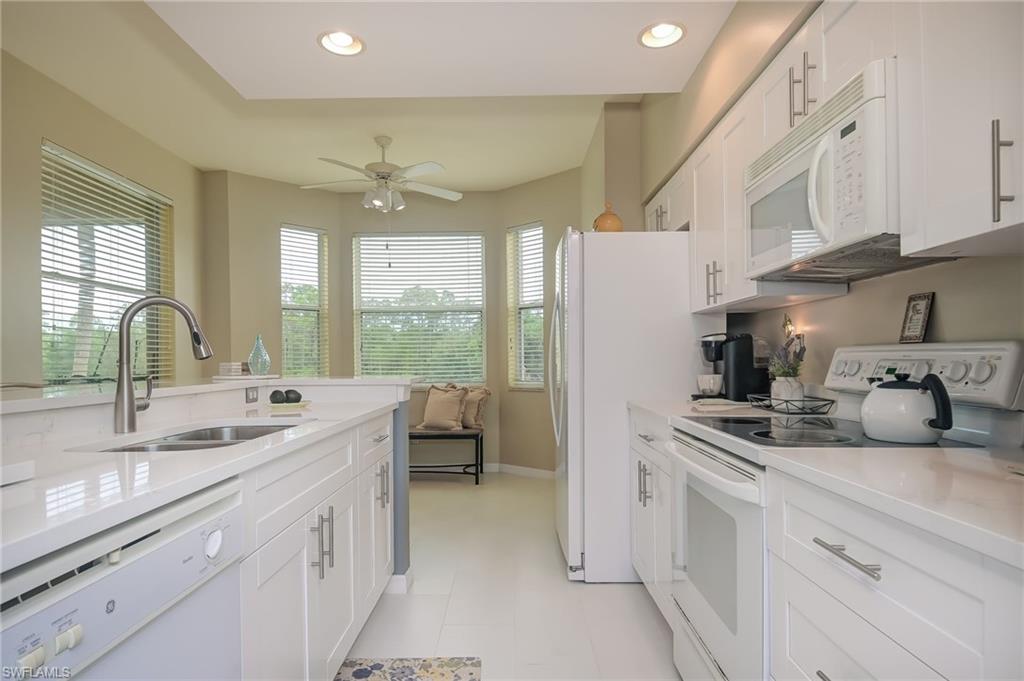 8670 Cedar Hammock Circle, Unit 223 Naples, FL 34112 - Photo 9 of 27 a kitchen with refrigerator a sink and cabinets