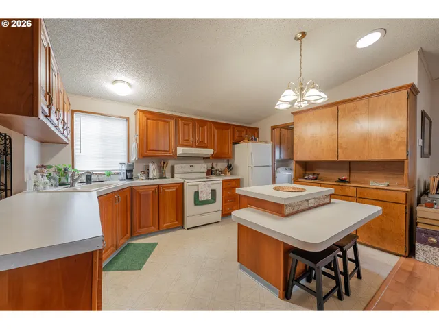 a kitchen with stainless steel appliances granite countertop a stove top oven a sink dishwasher a dining table and chairs with wooden floor