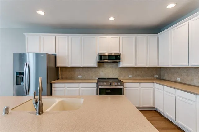 a kitchen with stainless steel appliances granite countertop white cabinets and refrigerator