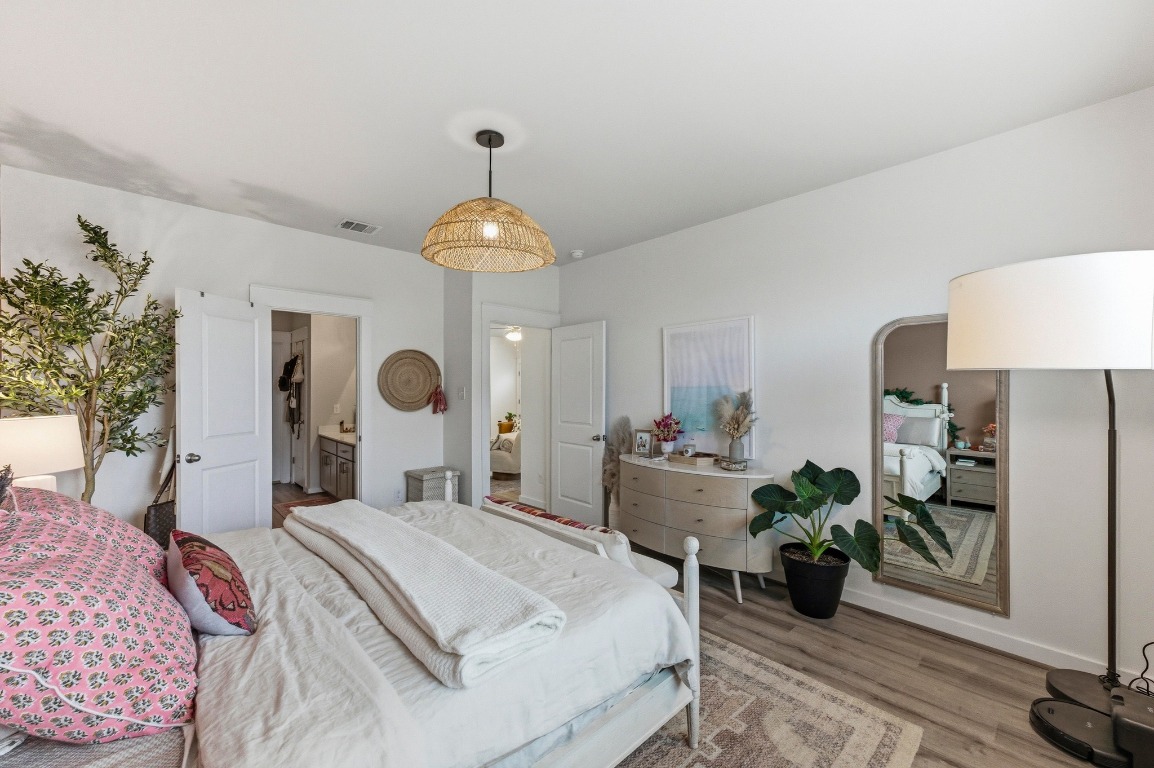 159 Threshing Road, Unit A Buda, TX 78610 - Photo 16 of 33 Bedroom featuring wood finished floors, connected bathroom, and arched walkways