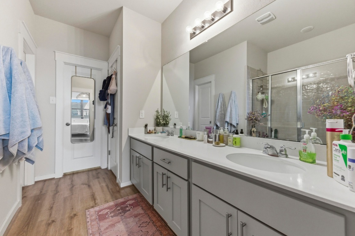 159 Threshing Road, Unit A Buda, TX 78610 - Photo 17 of 33 Bathroom with double vanity, light wood finished floors, and a shower stall