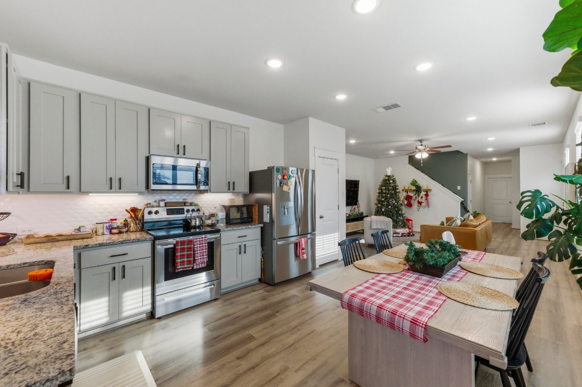 159 Threshing Road, Unit A Buda, TX 78610 - Photo 10 of 33 Kitchen featuring appliances with stainless steel finishes, light wood-type flooring, gray cabinetry, light stone countertops, and recessed lighting