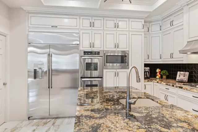 a kitchen with granite countertop a sink stainless steel appliances and white cabinets
