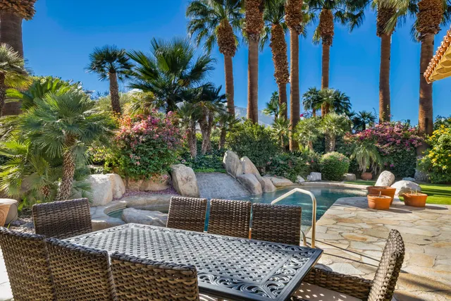 a front view of a house with swimming pool lawn chairs and a fire pit