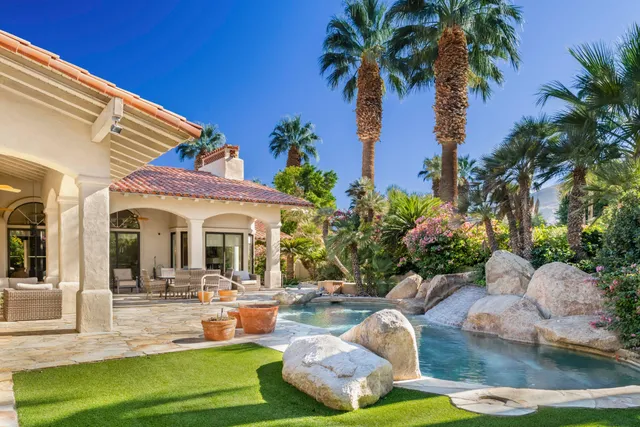 a view of a white house with swimming pool lawn chairs and a yard