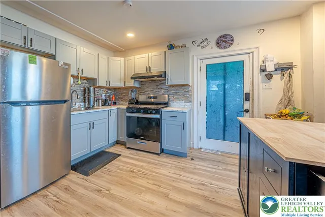 a kitchen with stainless steel appliances granite countertop a refrigerator a stove and a sink