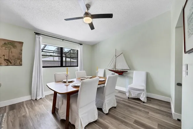 a dining room with wooden floor a chandelier fan a wooden table and chairs